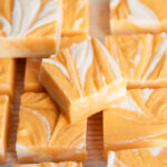 A pile of orange cream fudge marbled with white and orange fudge.