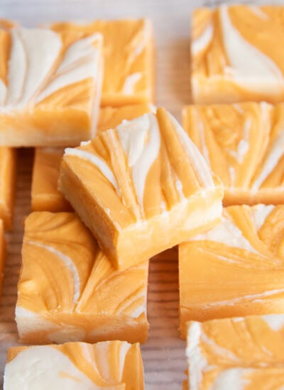 A pile of orange cream fudge marbled with white and orange fudge.