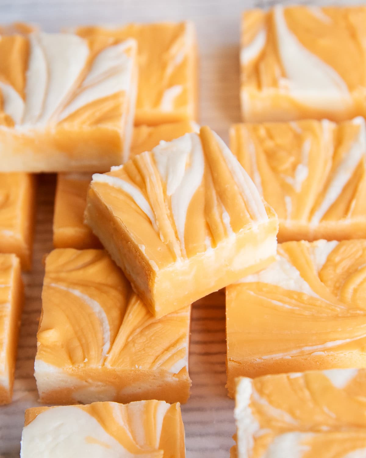 A pile of orange cream fudge marbled with white and orange fudge.