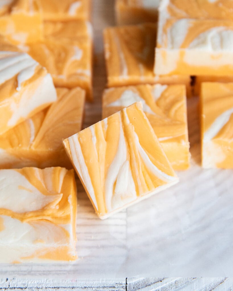 Rows of orange creamsicle fudge pieces that are marbled with vanilla and orange fudge.