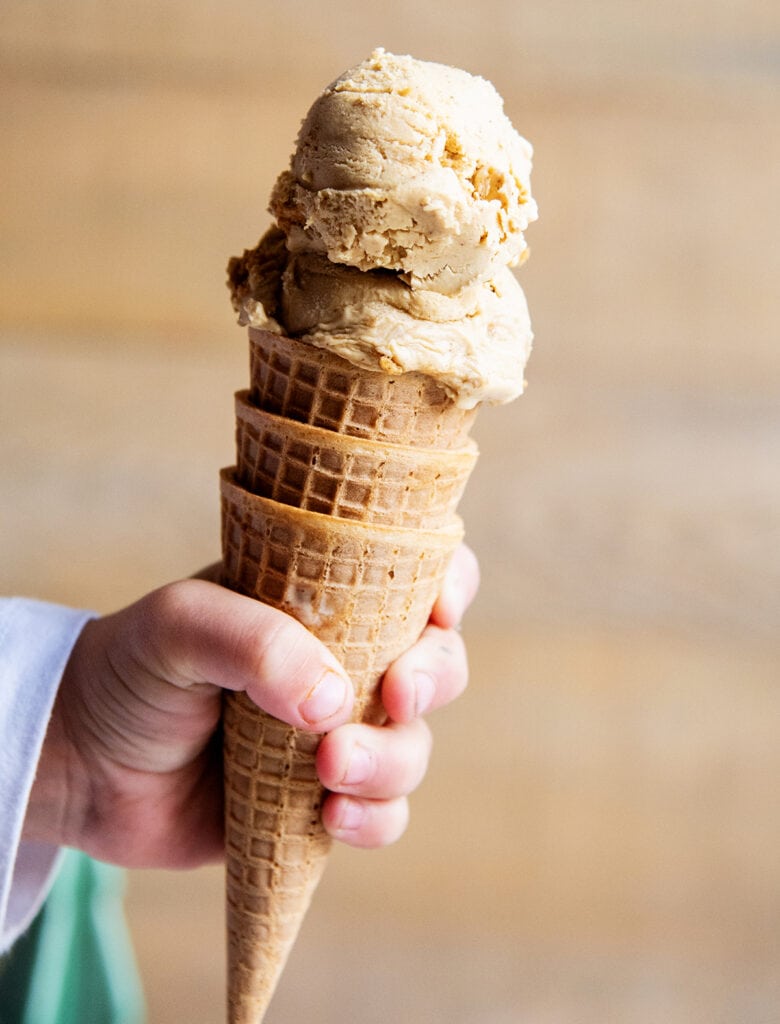 A hand holding a gingerbread ice cream cone. 
