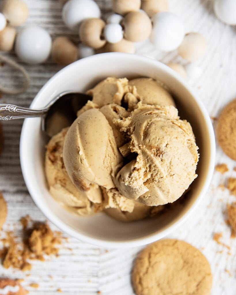 An above view of gingerbread ice cream in a white bowl, with a spoon in it.