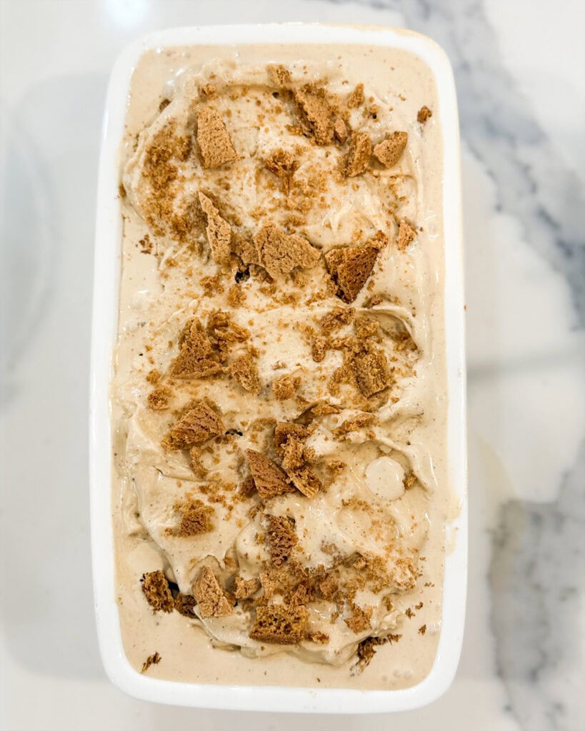 Gingerbread ice cream in a white bread pan topped with gingerbread cookies.