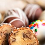 Two halves of a chocolate chip cookie dough truffle dipped in white chocolate.