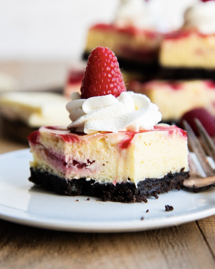 A piece of White Chocolate Raspberry cheesecake with a bite out of the front.