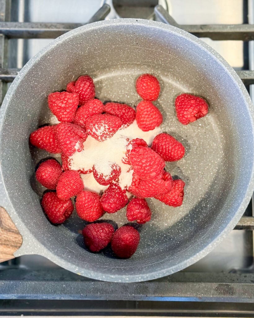 A pot of raspberries topped with sugar.