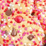 A pile of Valentine M&M cookies coated in red, white, and pink sprinkles.