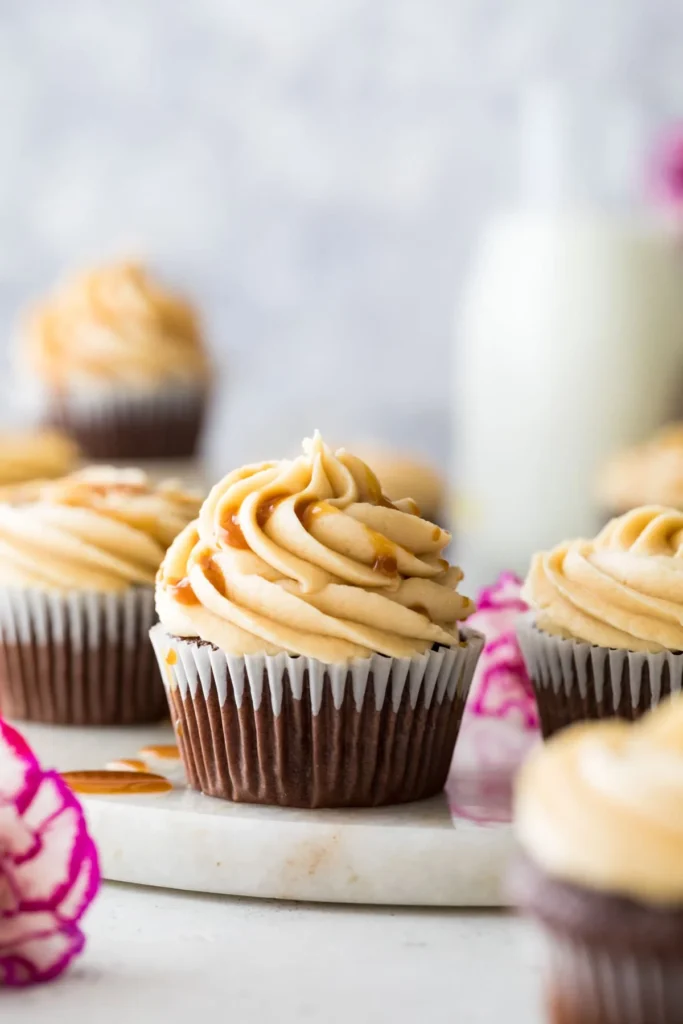 A cupcake topped with piped on caramel frosting and a drizzle of caramel sauce. 