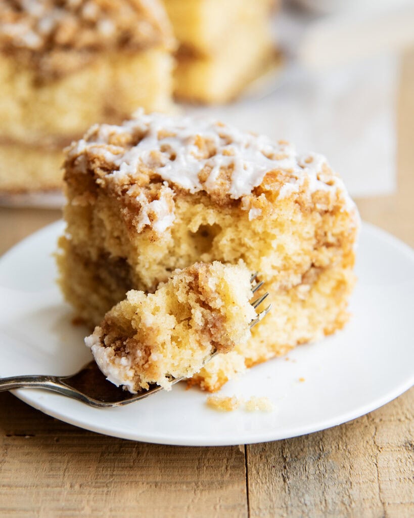 A fork of coffee cake next to a slice of it on a plate.