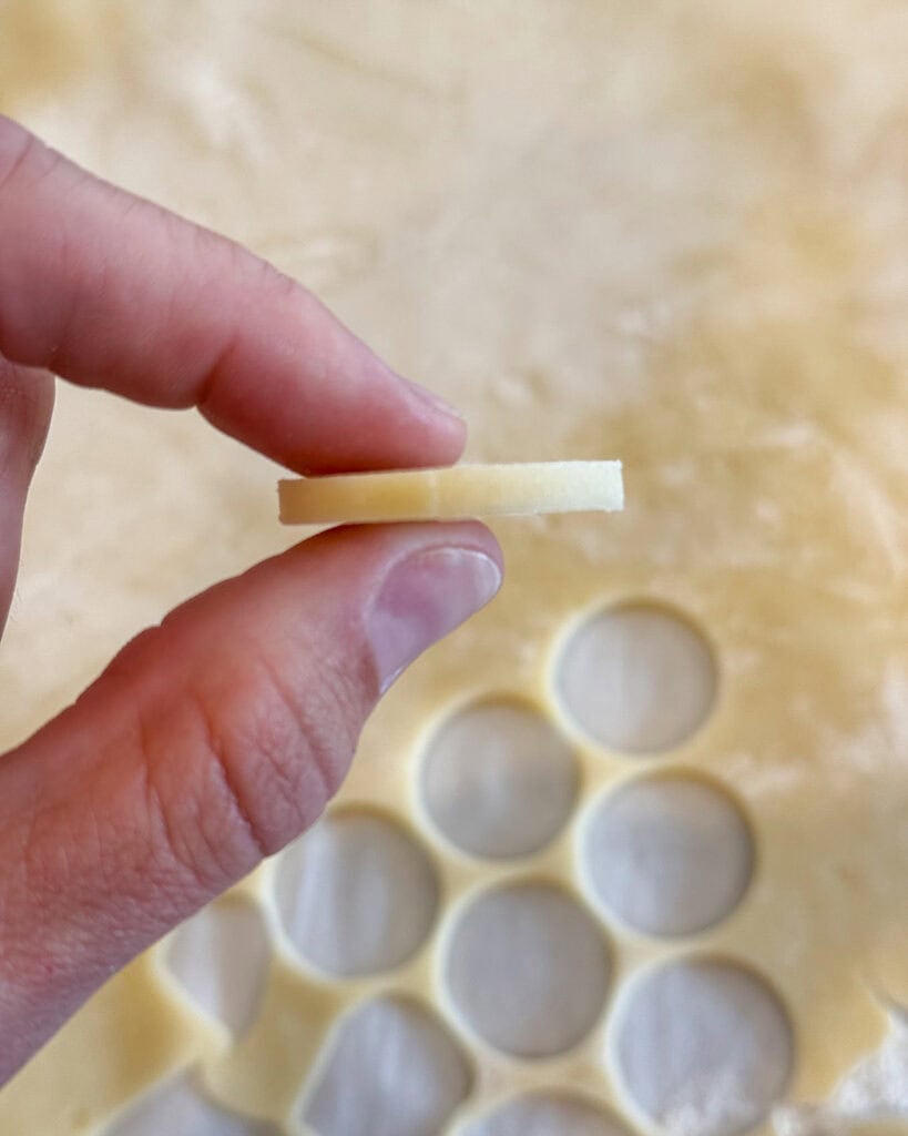 A hand holding a cream wafer cut out. 