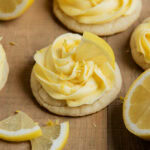 A lemon frosting topped sugar cookie, topped with a slice of lemon.
