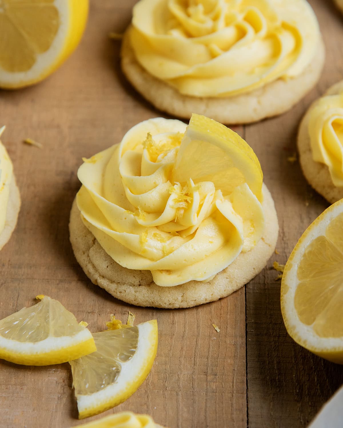 A lemon frosting topped sugar cookie, topped with a slice of lemon.