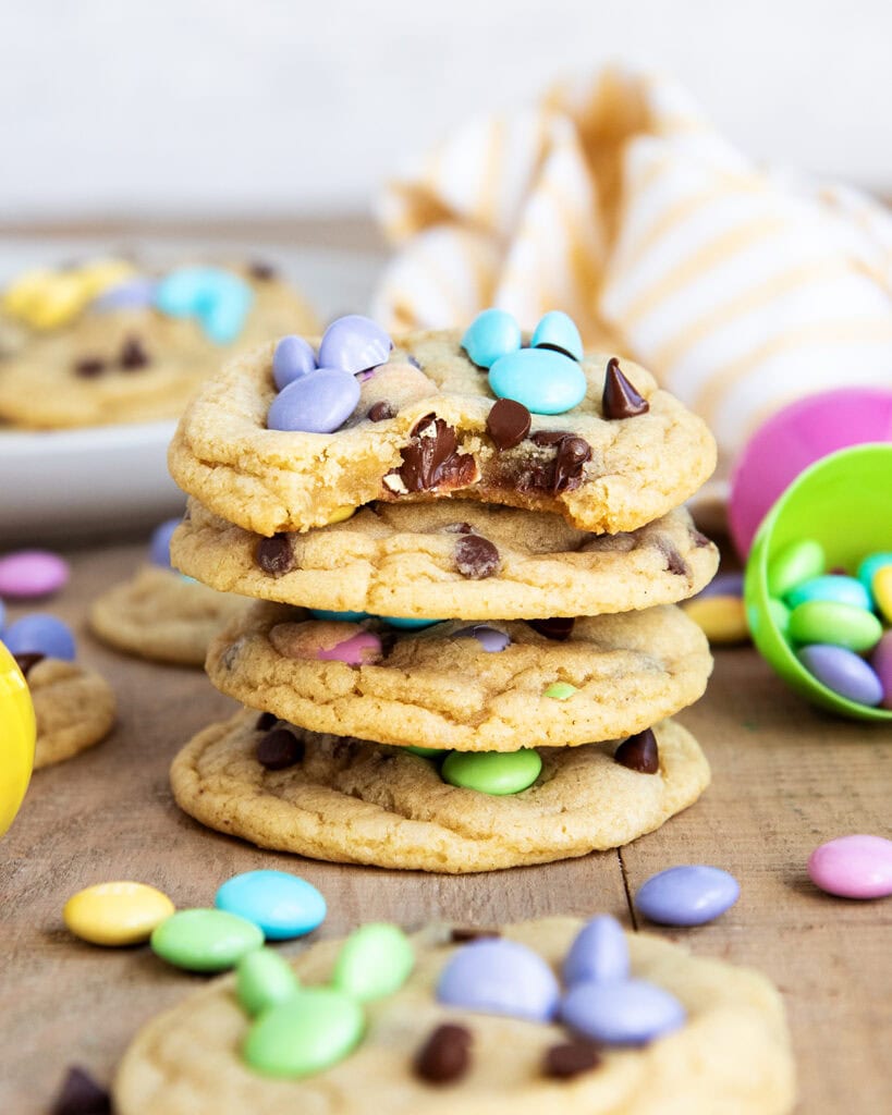 A stack of M&M Easter Bunny cookies, and the top cookie has a bite out of it.