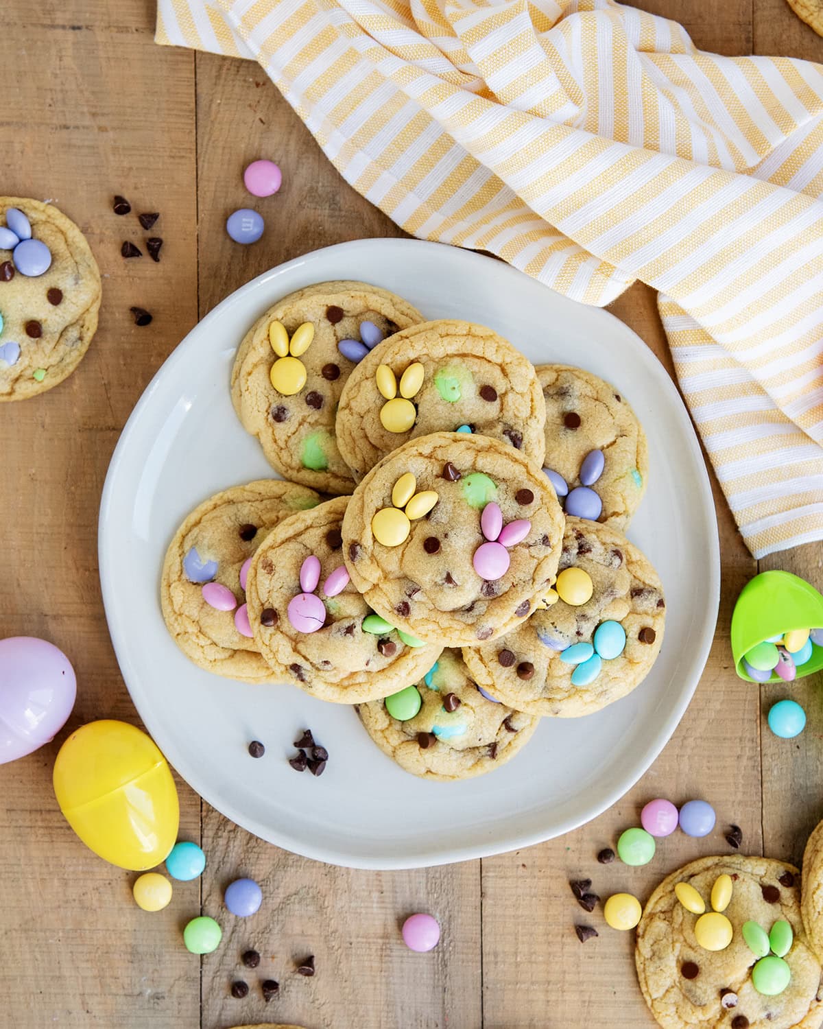 A plate of m&m cookies with mini chocolate chips and m&ms on top arraged to look like a bunny.