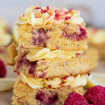 A stack of three raspberry lemon blondies with lemon frosting on top.