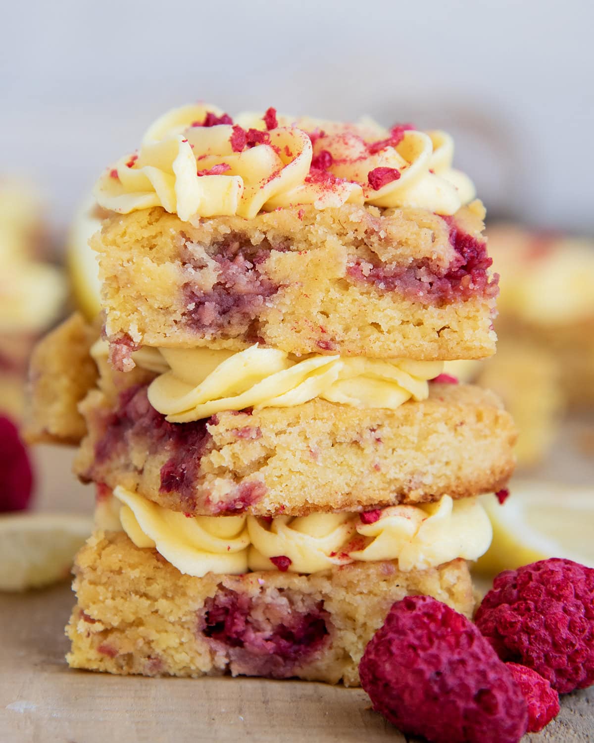 A stack of three raspberry lemon blondies with lemon frosting on top.