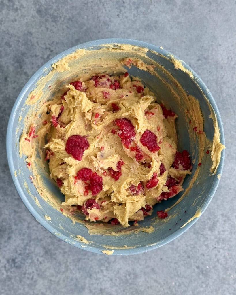 A bowl of lemon cookie dough with fresh raspberries.