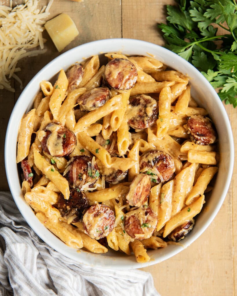 A bowl of penne pasta and sausage coated in a creamy cajun alfredo sauce.