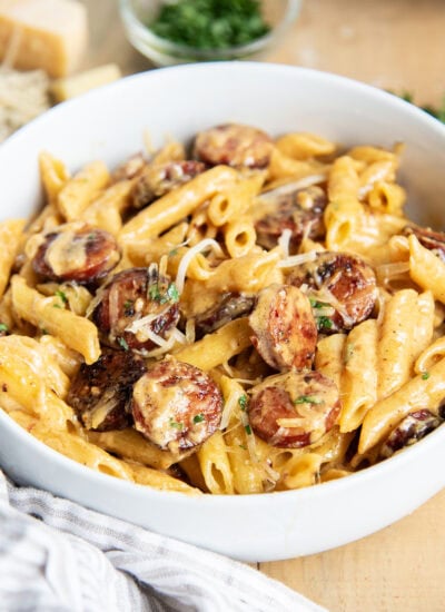 A bowl of penne pasta and sausage coated in a creamy cajun alfredo sauce.