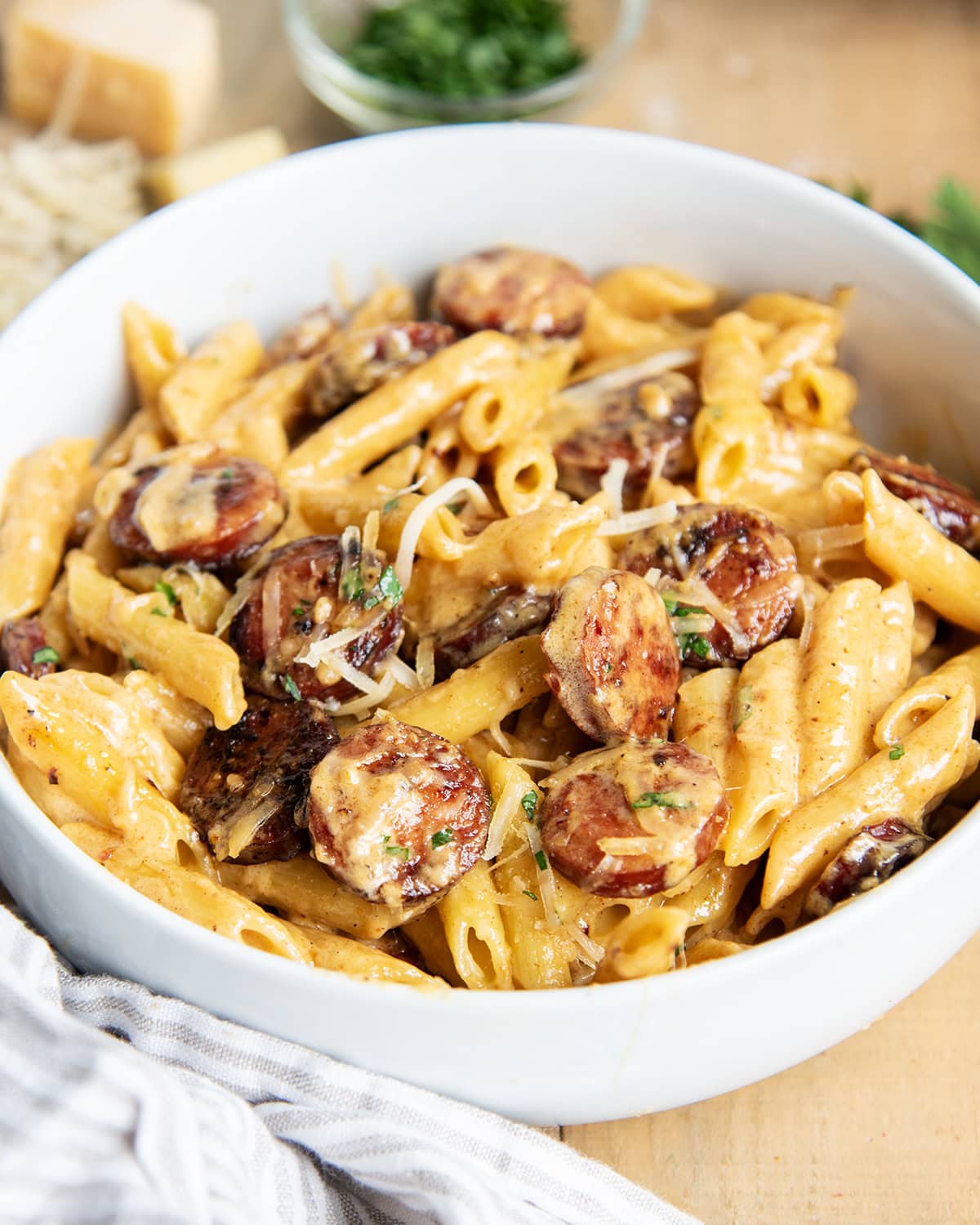 A bowl of penne pasta and sausage coated in a creamy cajun alfredo sauce.