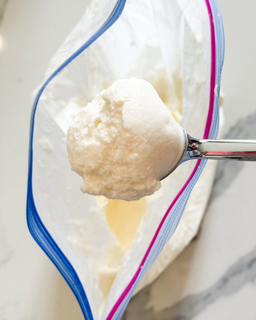 A coop of a very soft ice cream above a bag.