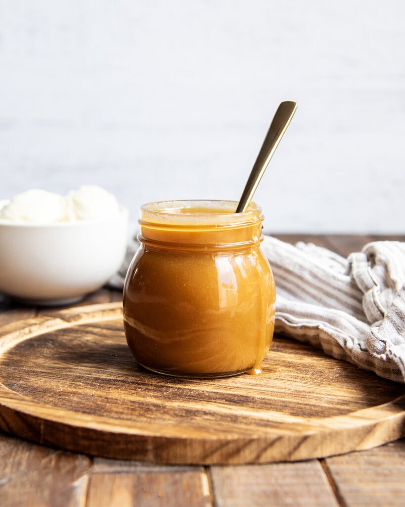 A jar of homemade butterscotch cause on a wooden board.