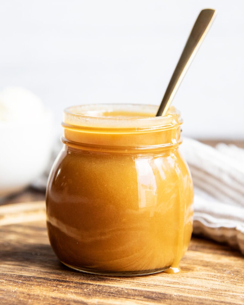 A jar of homemade butterscotch cause on a wooden board.