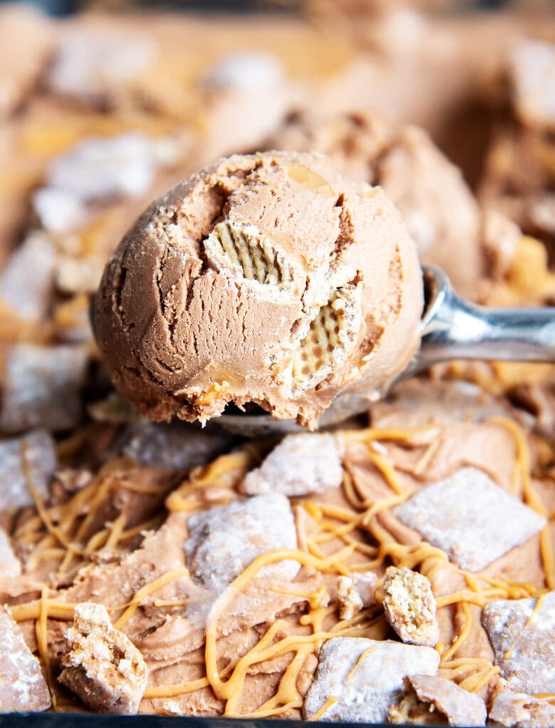 A scoop of chocolate ice cream with chex pieces and peanut butter swirled in it.