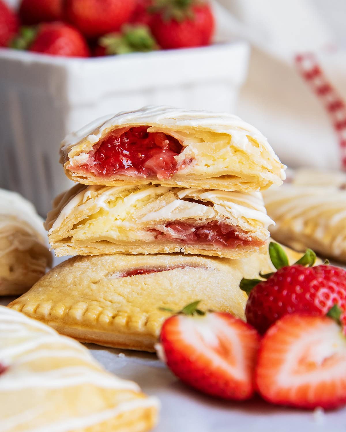 A stack of strawberry cheesecake hand pies and two are cut in half showing the filling.