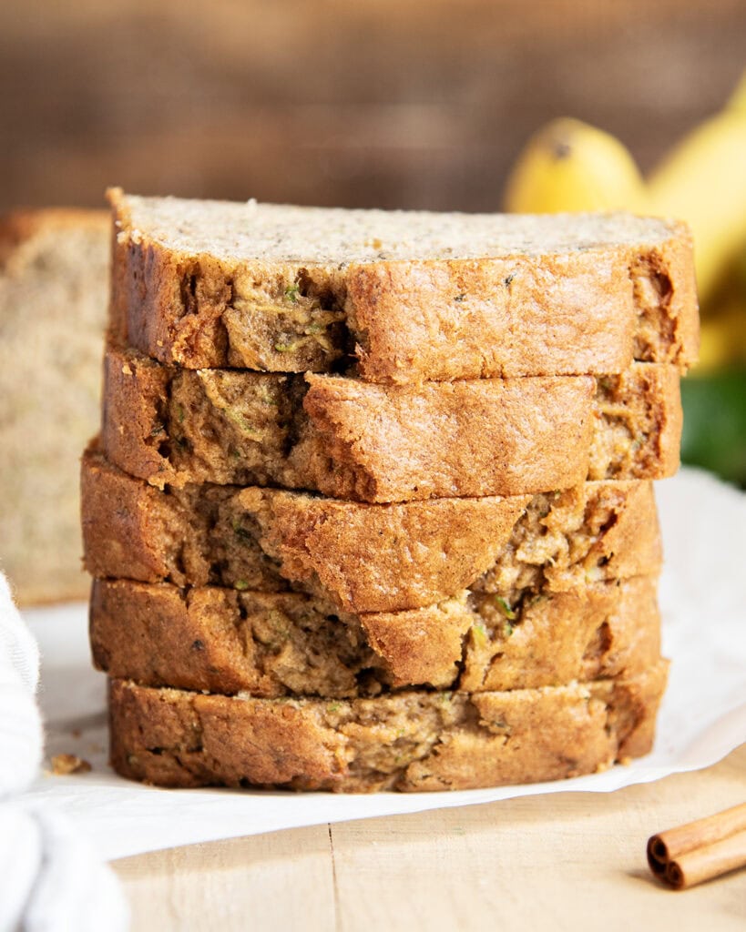 A stack of slices of banana zucchini bread on a piece of parchment paper.