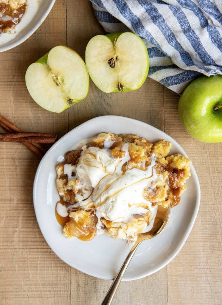 An above view of a plate of apple dump cake with ice cream melting on top.