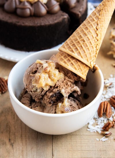 A bowl of German Chocolate Ice Cream topped with a scoop of coconut pecan frosting, and two ice cream cones.