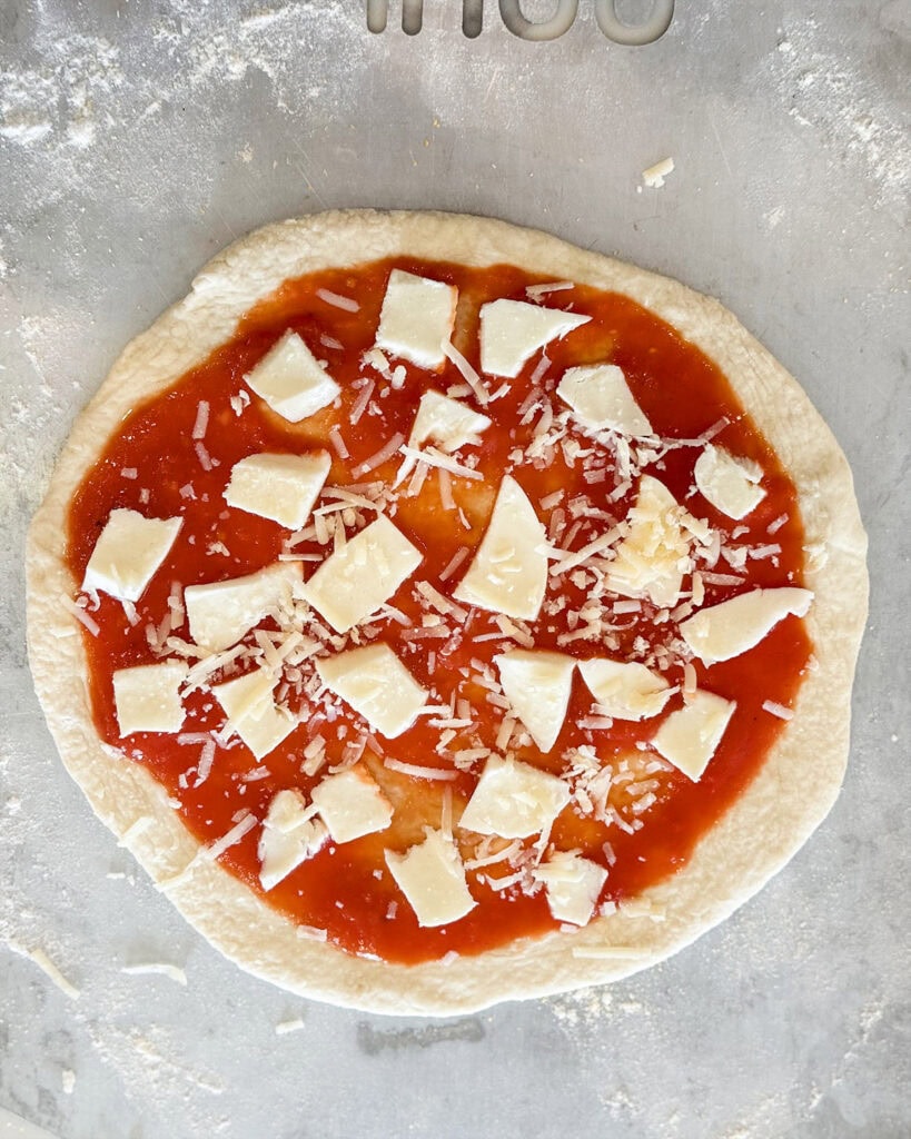 A pizza dough crust topped with sauce and cheese.