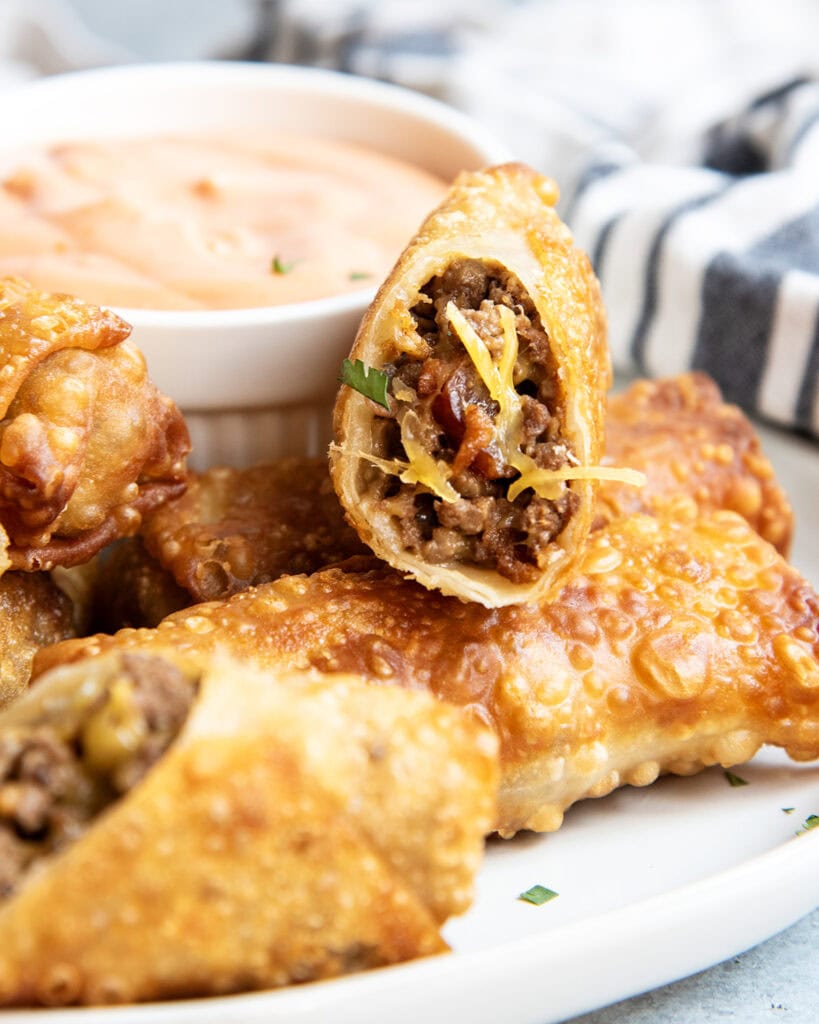 A pile of cheeseburger egg rolls on a plate.