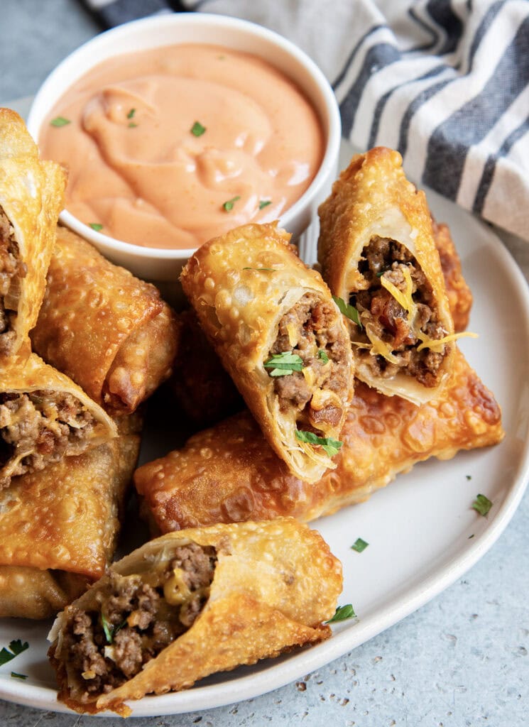 A pile of cheeseburger egg rolls on a plate.