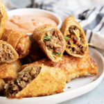 A pile of cheeseburger egg rolls on a plate.