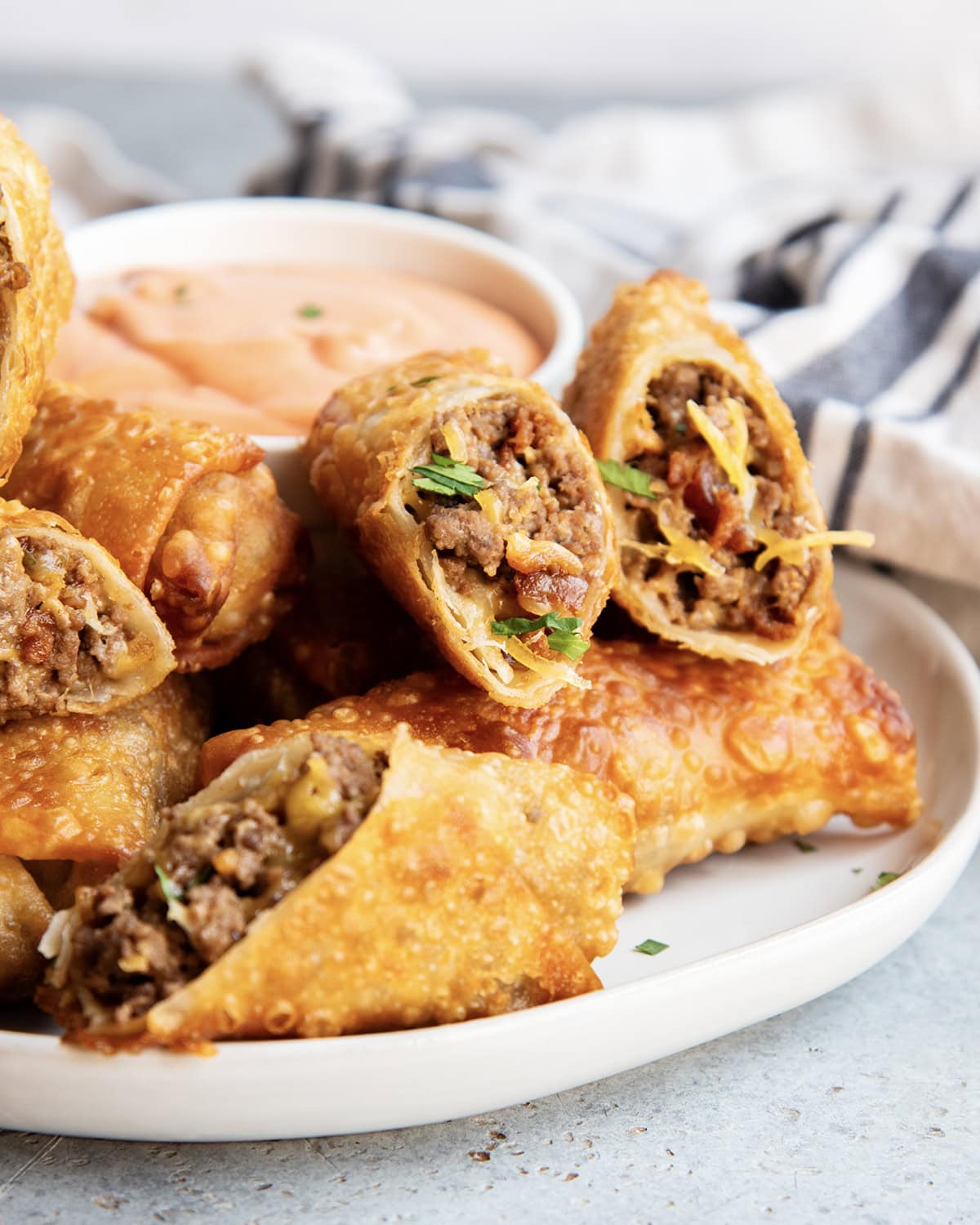 A pile of cheeseburger egg rolls on a plate.