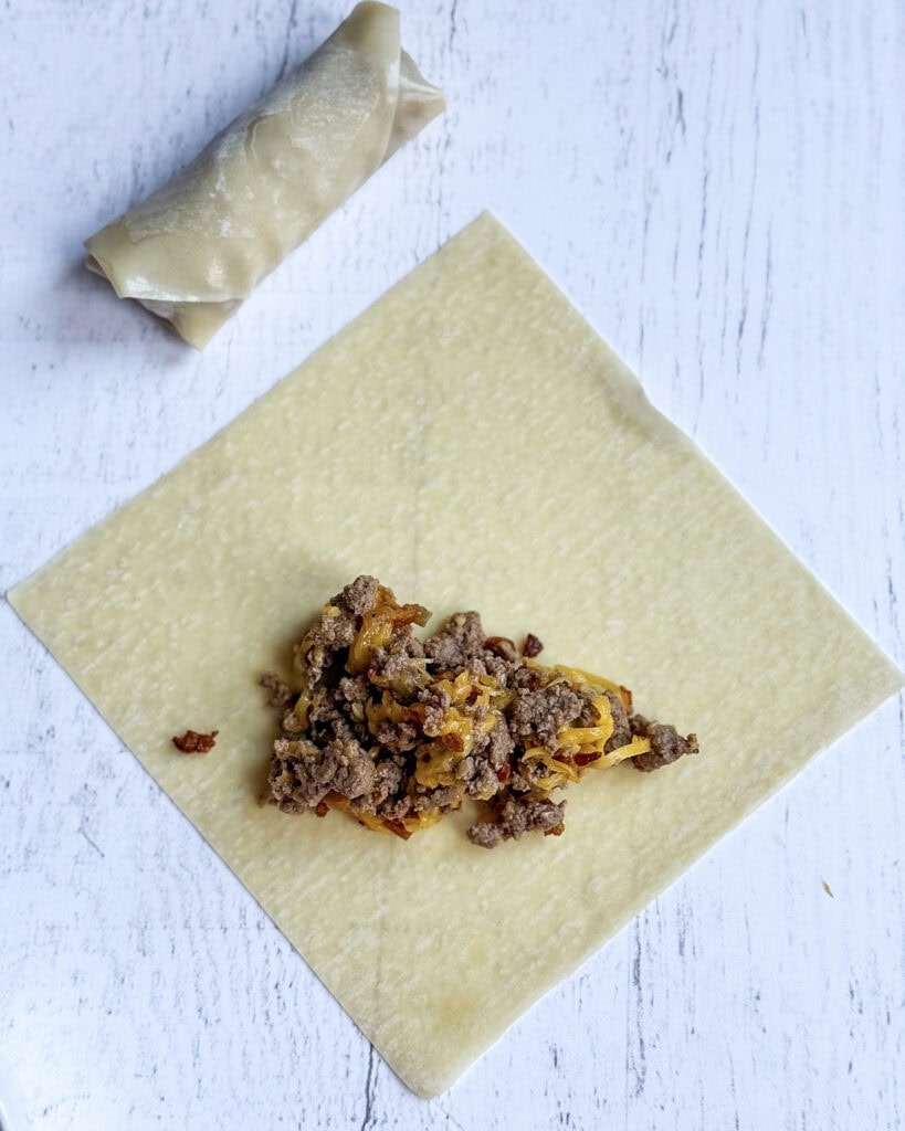 Cooked ground beef on an egg roll wrapper.