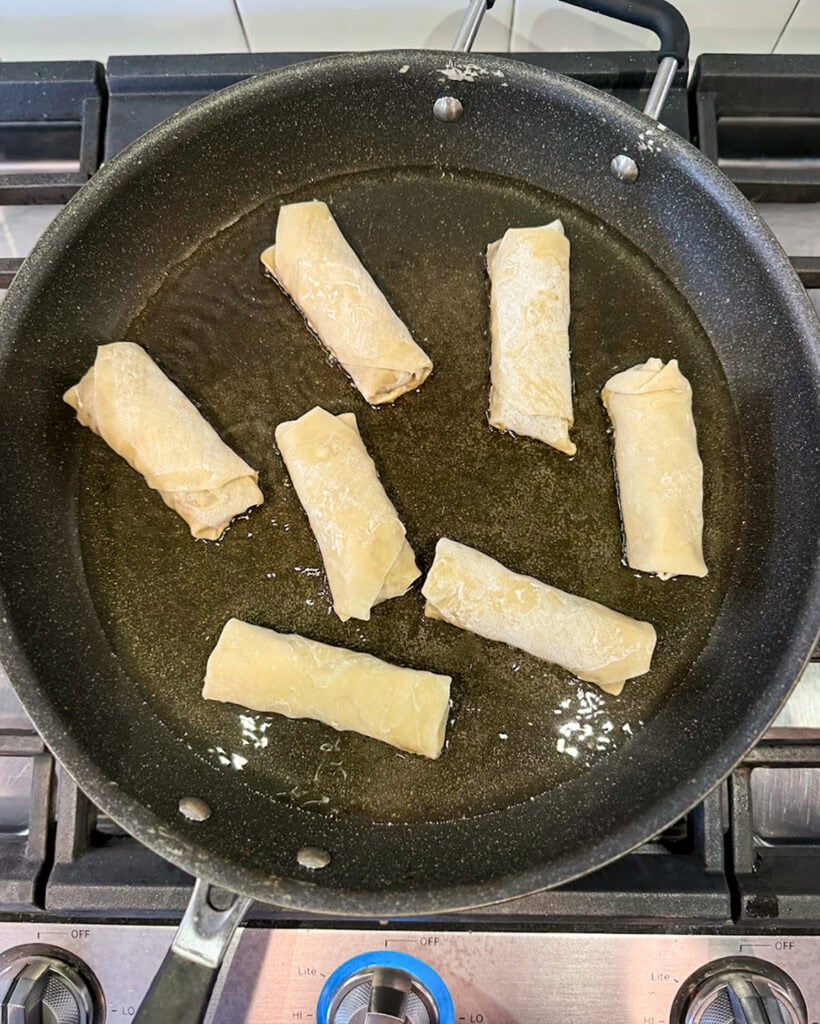 Egg Rolls frying in a skillet.