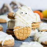 A Nutter Butter Cookie decorated with white chocolate and candy eyes to look like mummies.