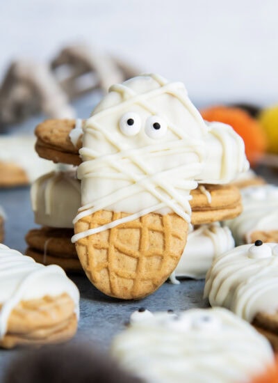 A Nutter Butter Cookie decorated with white chocolate and candy eyes to look like mummies.