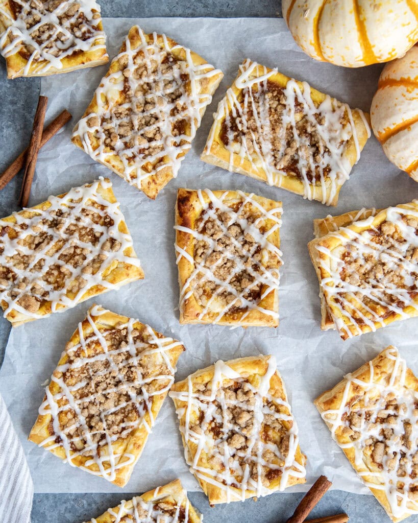 An above view of pumkin danishes stopped with a crumb topping and vanilla icing.
