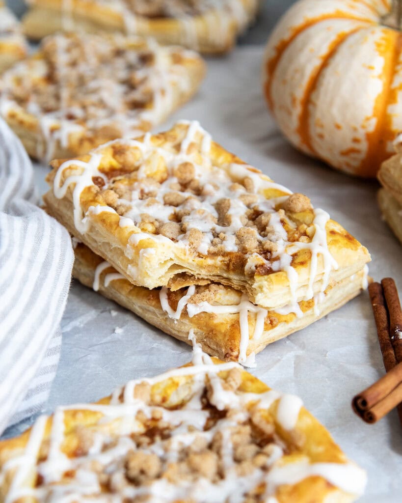 A stack of two pumpkin danishes, and one has a bite out of it.