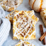 A pumpkin danish laying on another danish on a piece of parchment paper.