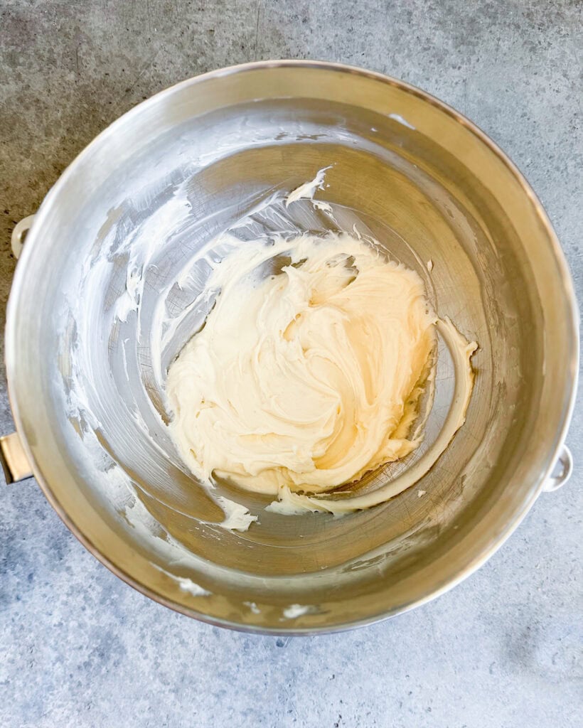 A metal mixing bowl with a sweetebed cream cheese .