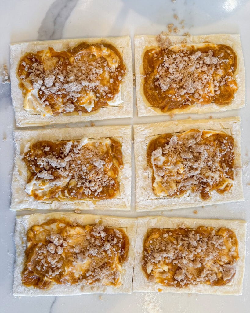 Unbaked pumpkin cream cheese danishes with cream cheese swirled with pumpkin and topped with crumb topping.