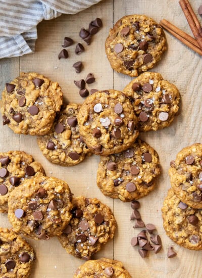 A pile of pumpkin oatmeal chocolaet chip cookies on a wooden table.