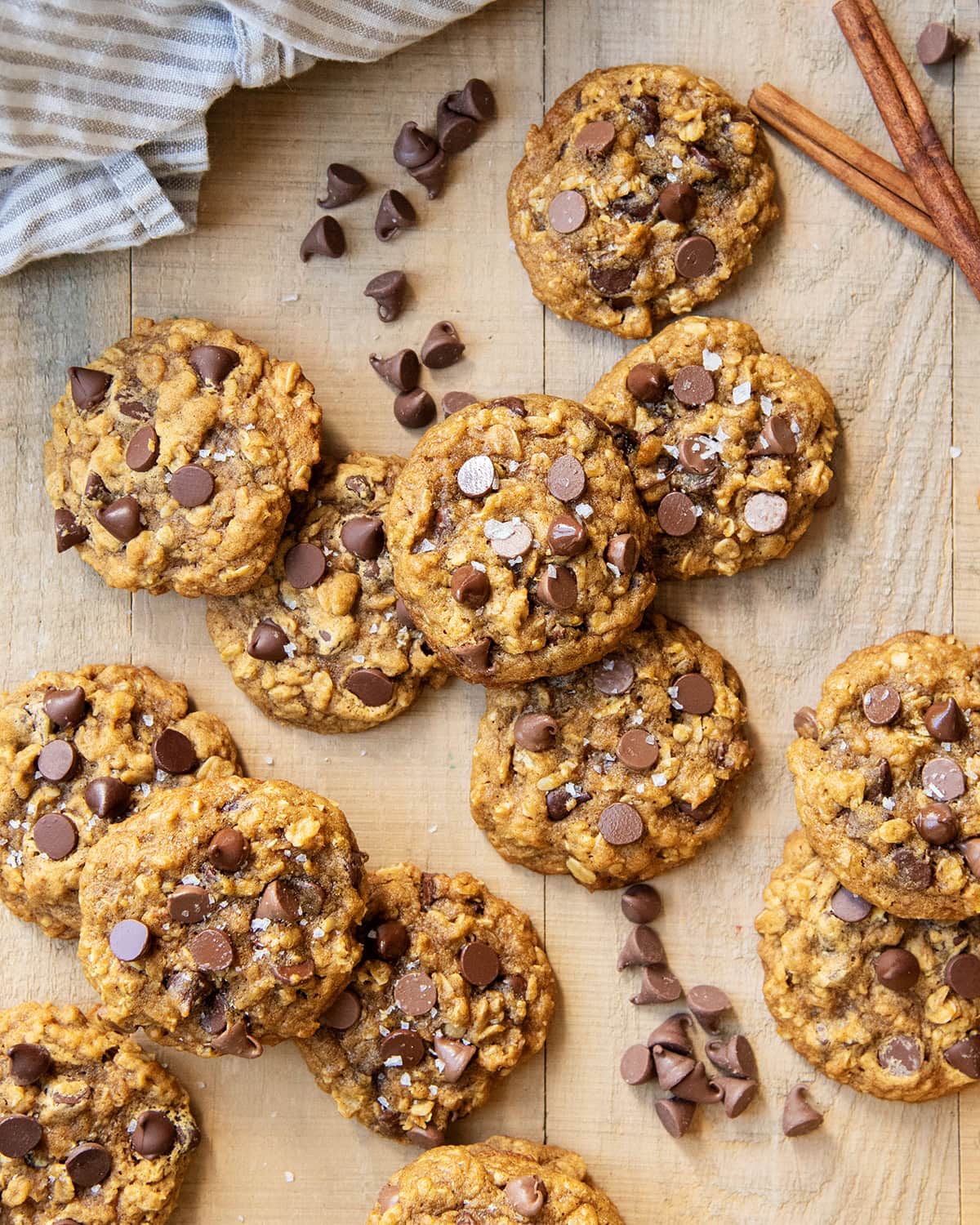 A pile of pumpkin oatmeal chocolaet chip cookies on a wooden table.