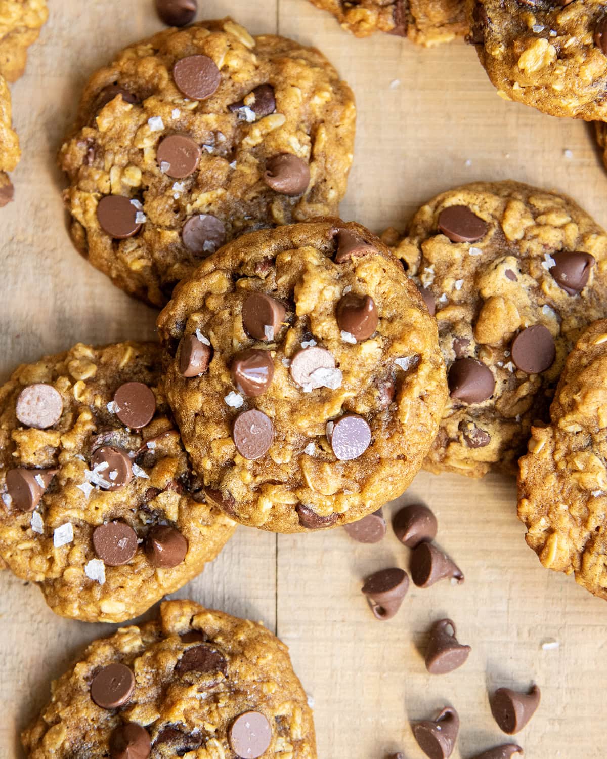 A pile of pumpkin oatmeal chocolaet chip cookies on a wooden table.