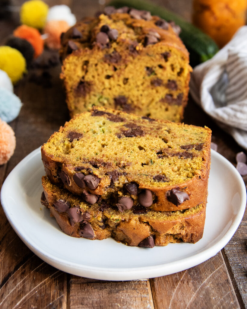 A stack of two pieces of pumpkin chocolate chip bread on a white plate. 